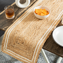 Load image into Gallery viewer, Woven table runner on a wooden table with a glass of amber liquid and a bowl of orange chips.