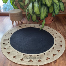 Load image into Gallery viewer, Round jute rug with black center on a wooden floor, surrounded by plants and a small stool.