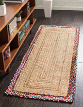 Load image into Gallery viewer, A rectangular, flatweave natural jute rug with multicolored borders, placed on a hardwood floor in a home setting, near a bookshelf and a white wall sconce.