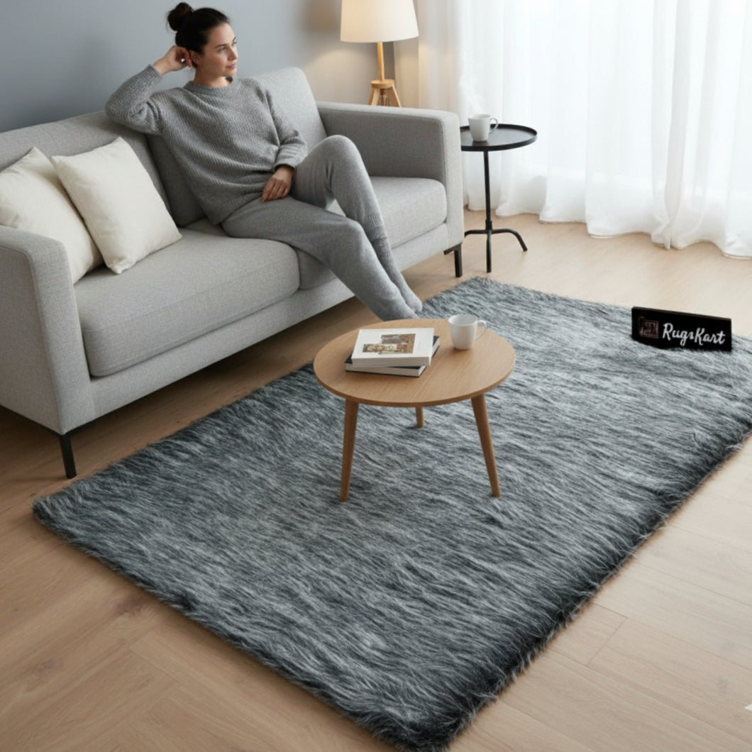 Woman sitting on a gray sofa with a textured gray rug in a living room.