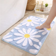 Load image into Gallery viewer, Bathroom mat with daisy pattern on a light blue background, foot stepping onto it.
