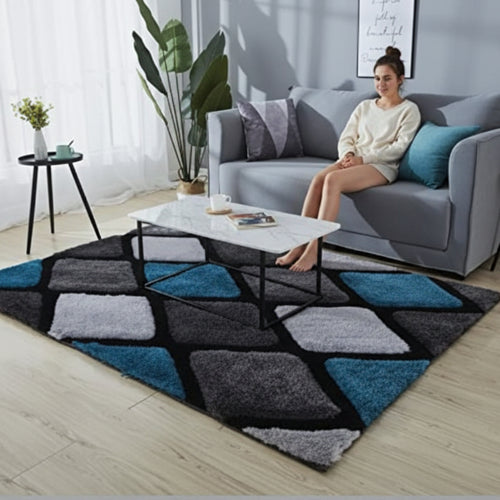 Woman sitting on a gray sofa in a living room with a geometric patterned rug.
