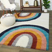 Load image into Gallery viewer, Multicolored rainbow-shaped rug on a wooden floor with a chair, ottoman, and plant in the background.
