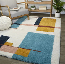 Load image into Gallery viewer, Colorful geometric-patterned rug in a living room setting with a chair and shelves.
