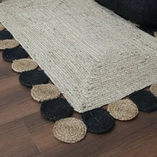 Load image into Gallery viewer, Textured rug with black and beige circular patterns on a wooden floor
